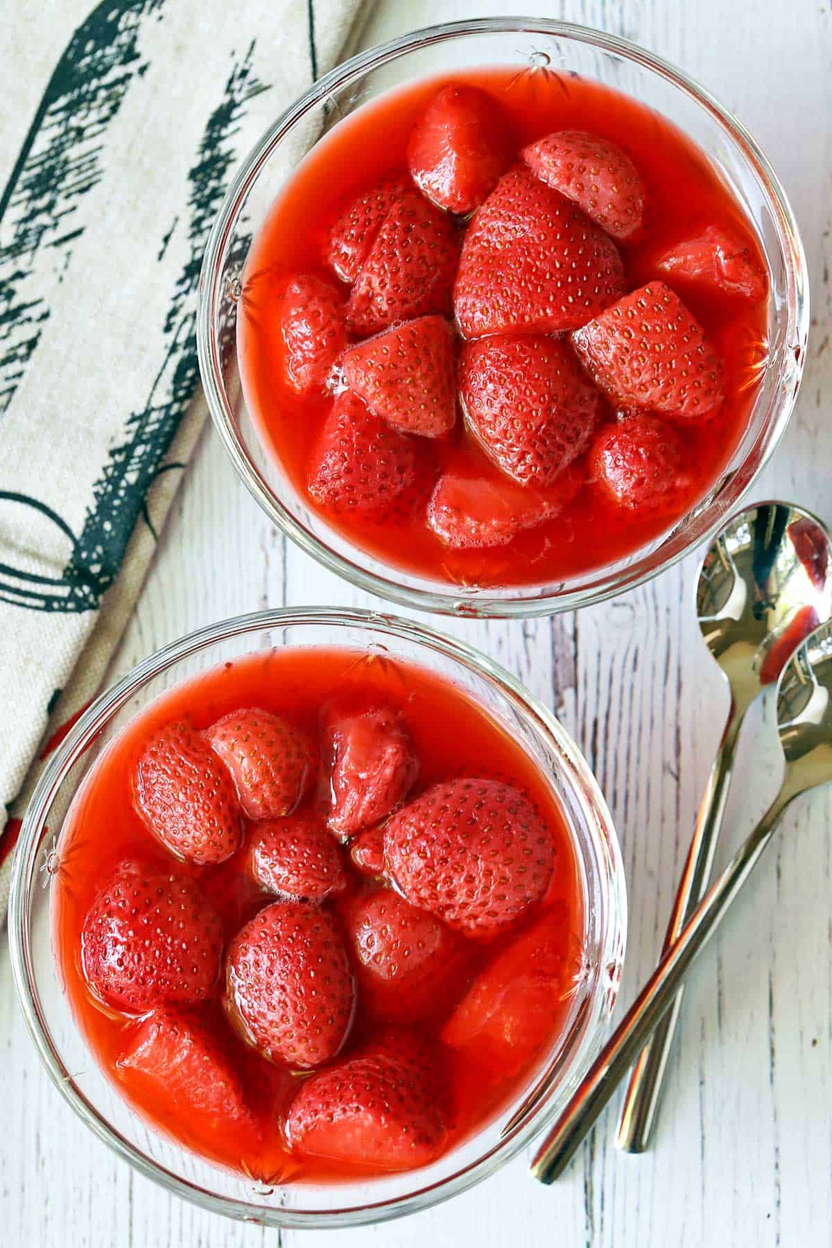 Strawberry compote is served in dessert glasses with two teaspoons. 
