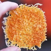 A keto cheese cracker is held up in the air.