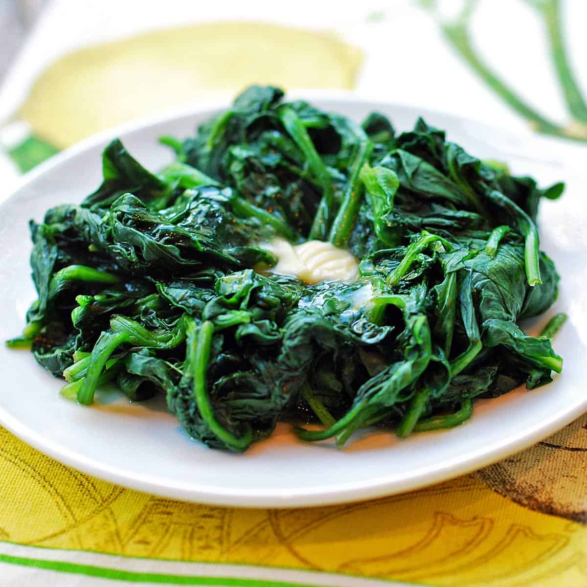 Steamed spinach is topped with melted butter.