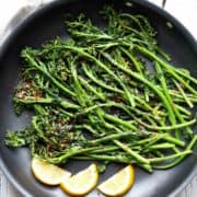Sauteed broccolini is served with lemon slices.