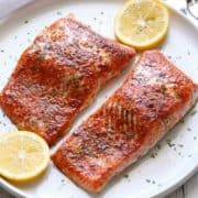 Paprika salmon is served with lemon slices.