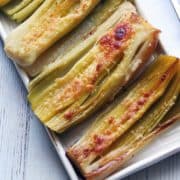 Roasted leeks are served on a white tray.