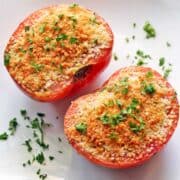 Broiled tomatoes are topped with chopped parsley.