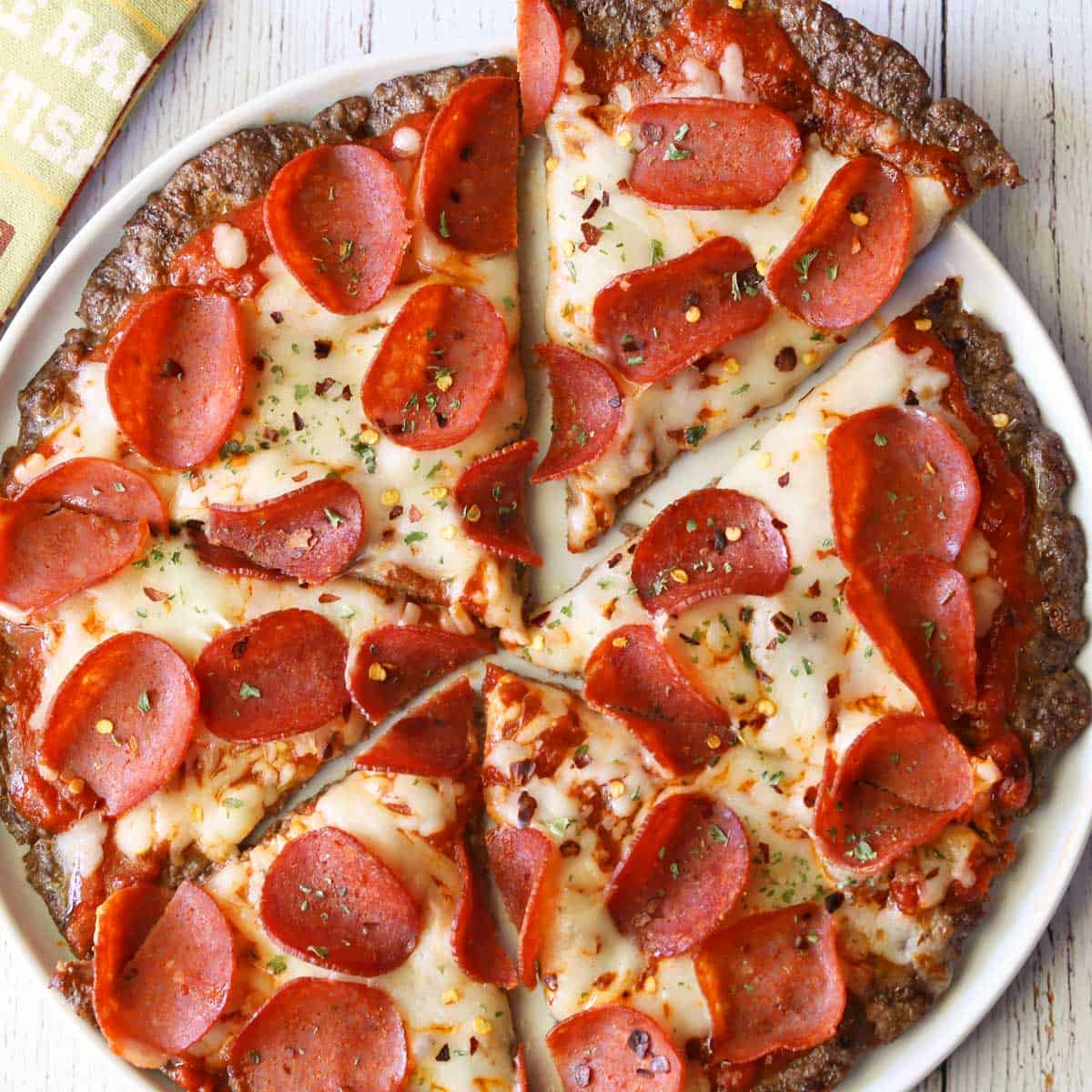 Meatzza, sliced, is served on a white plate with a napkin.