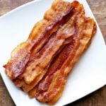 Oven bacon is served on a white plate.