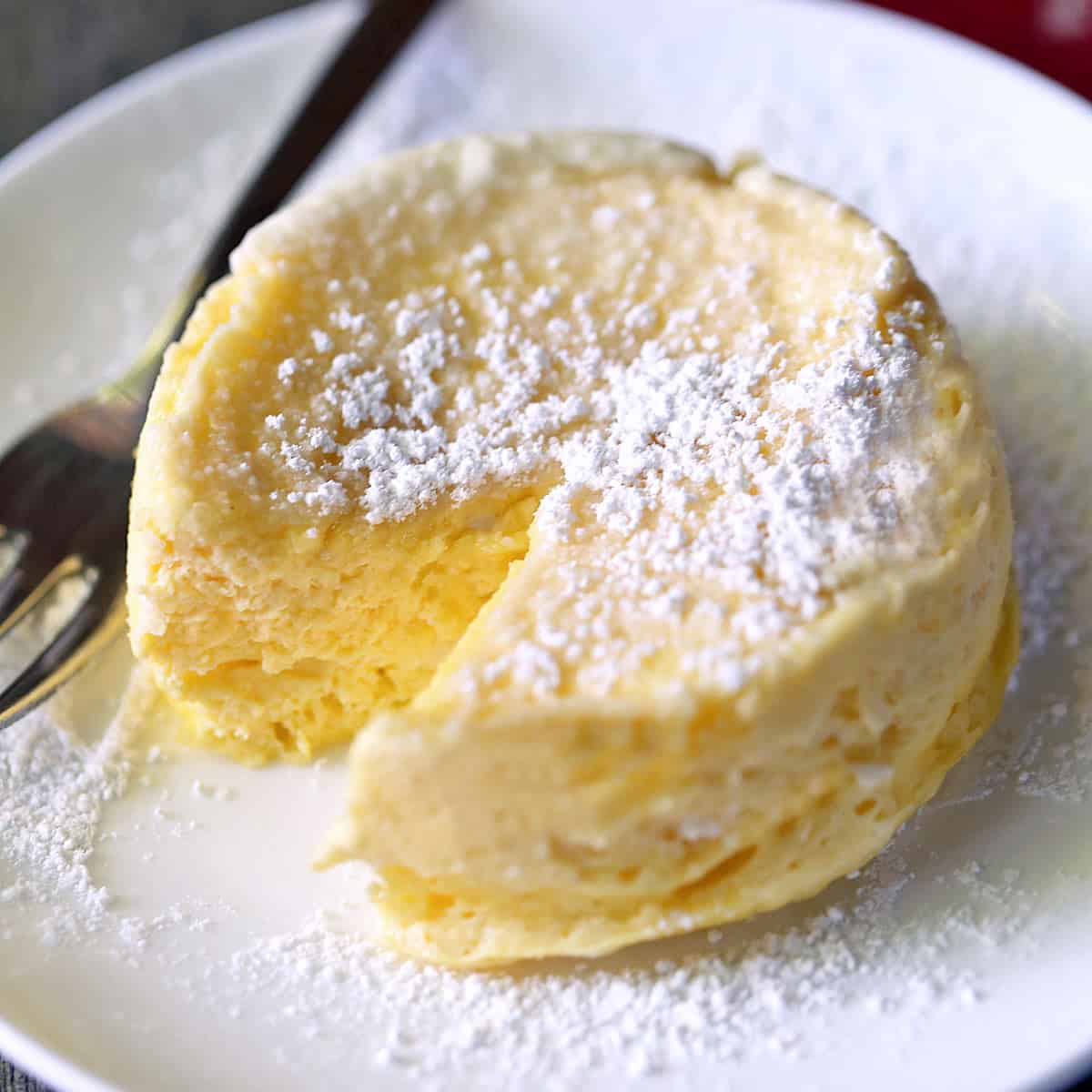 Microwave cheesecake is served on a white plate with a fork.