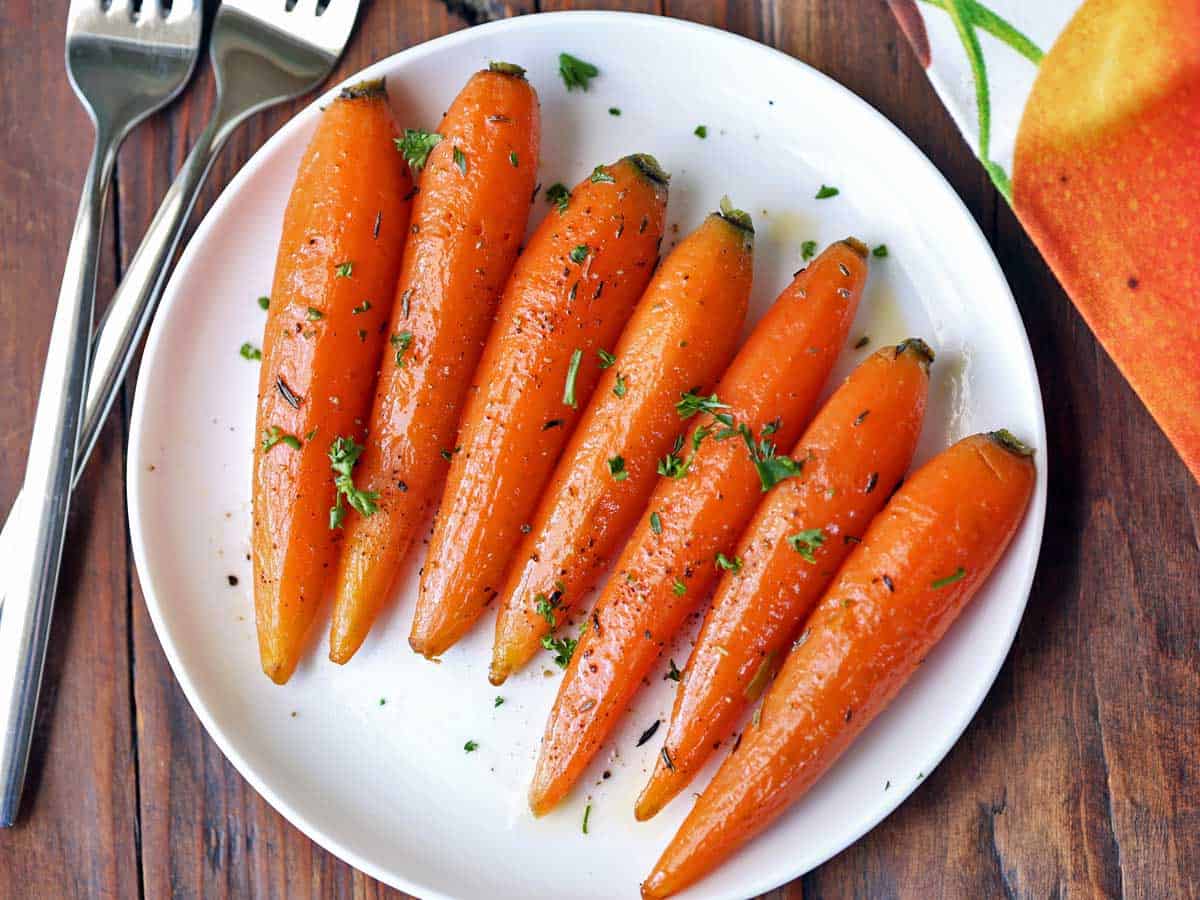 Petite glazed carrots served on a white plate.