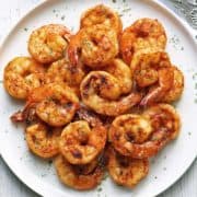 Broiled shrimp are served on a white plate.
