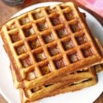 Keto waffles are stacked on a white plate.