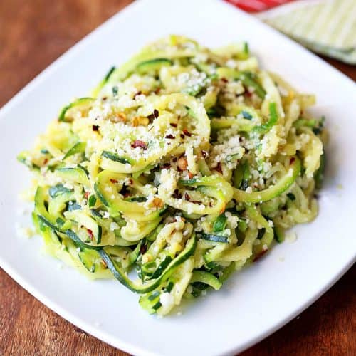 Zucchini noodles are piled on a white plate.