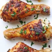 Baked chicken drumsticks are served on a white plate.