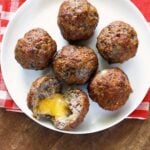 Cheese stuffed meatballs are served on a white plate with a napkin.
