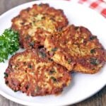 Three tuna patties are served on a white plate, garnished with parsley.