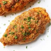 Parmesan-crusted chicken is topped with chopped parsley.