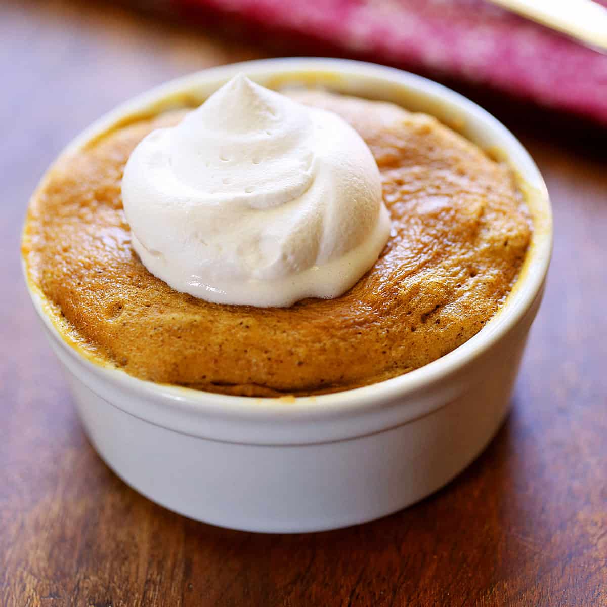 Keto peanut butter mug cake is topped with whipped cream.
