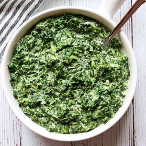 Creamed spinach is served in a white bowl.