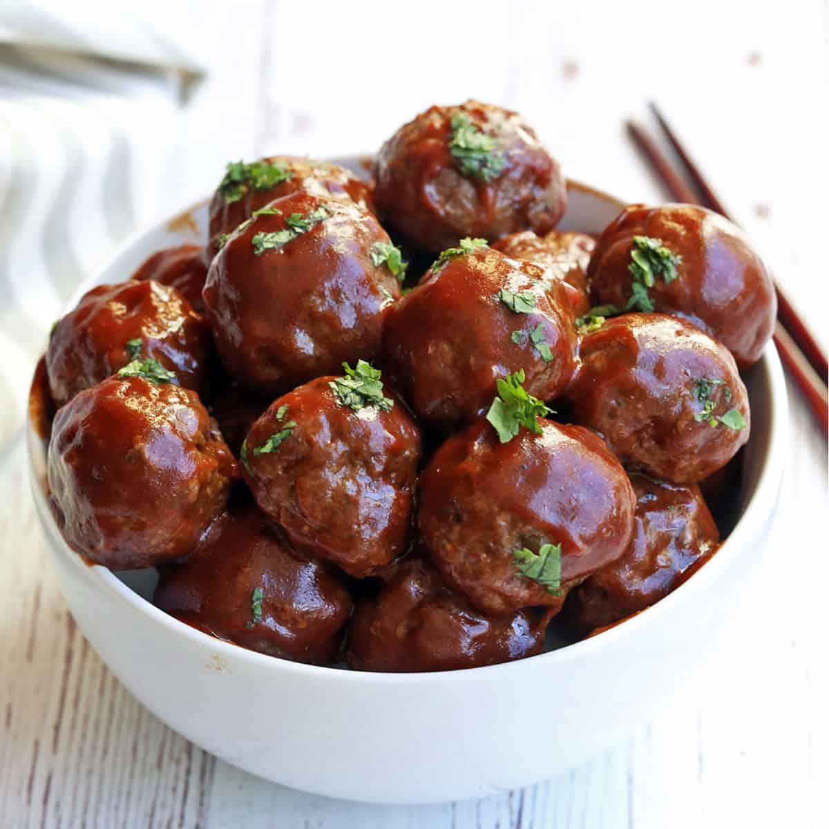 Sweet and sour meatballs are served with chopsticks.