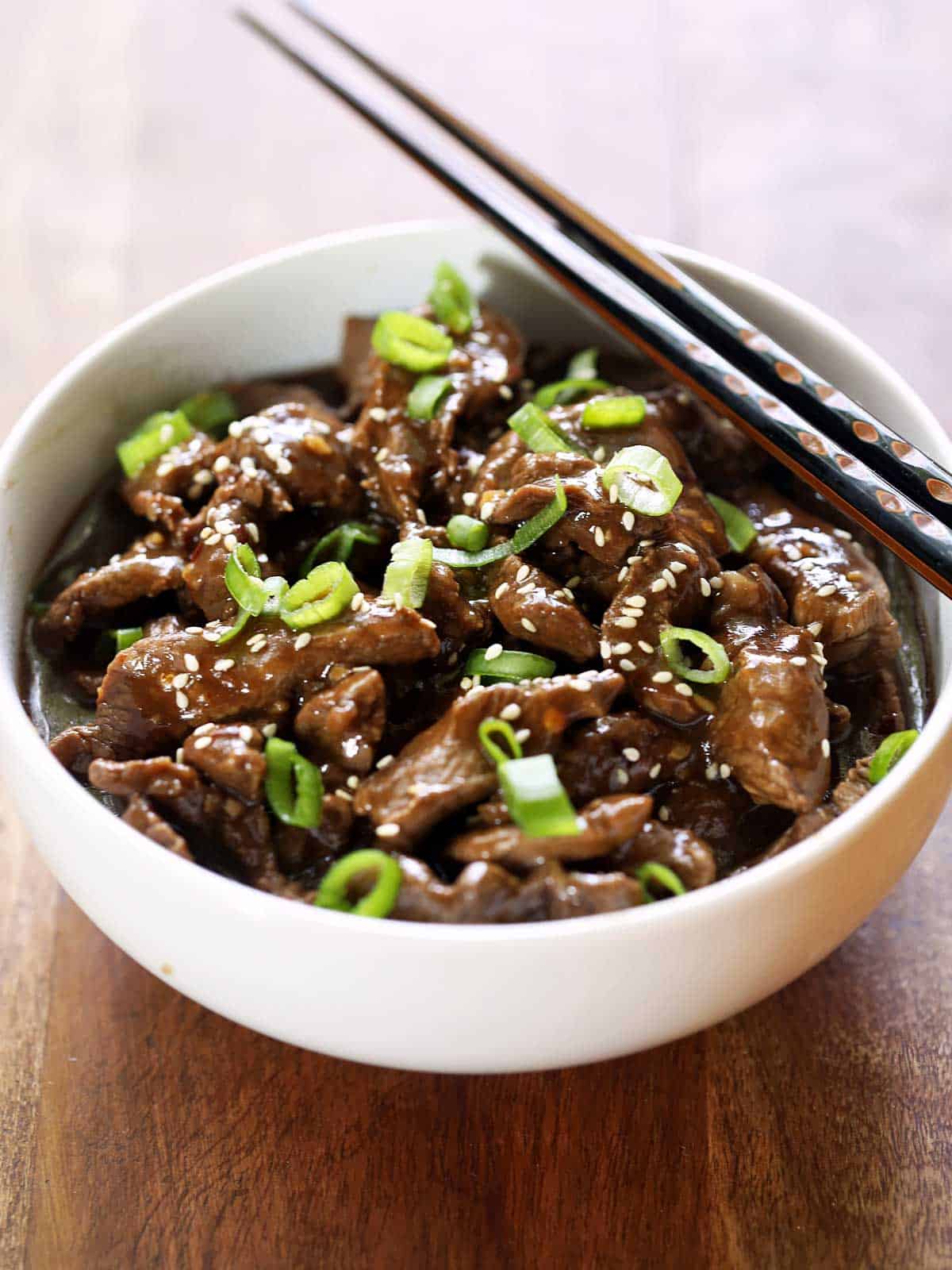 Korean beef is served in a white bowl with chopsticks. 