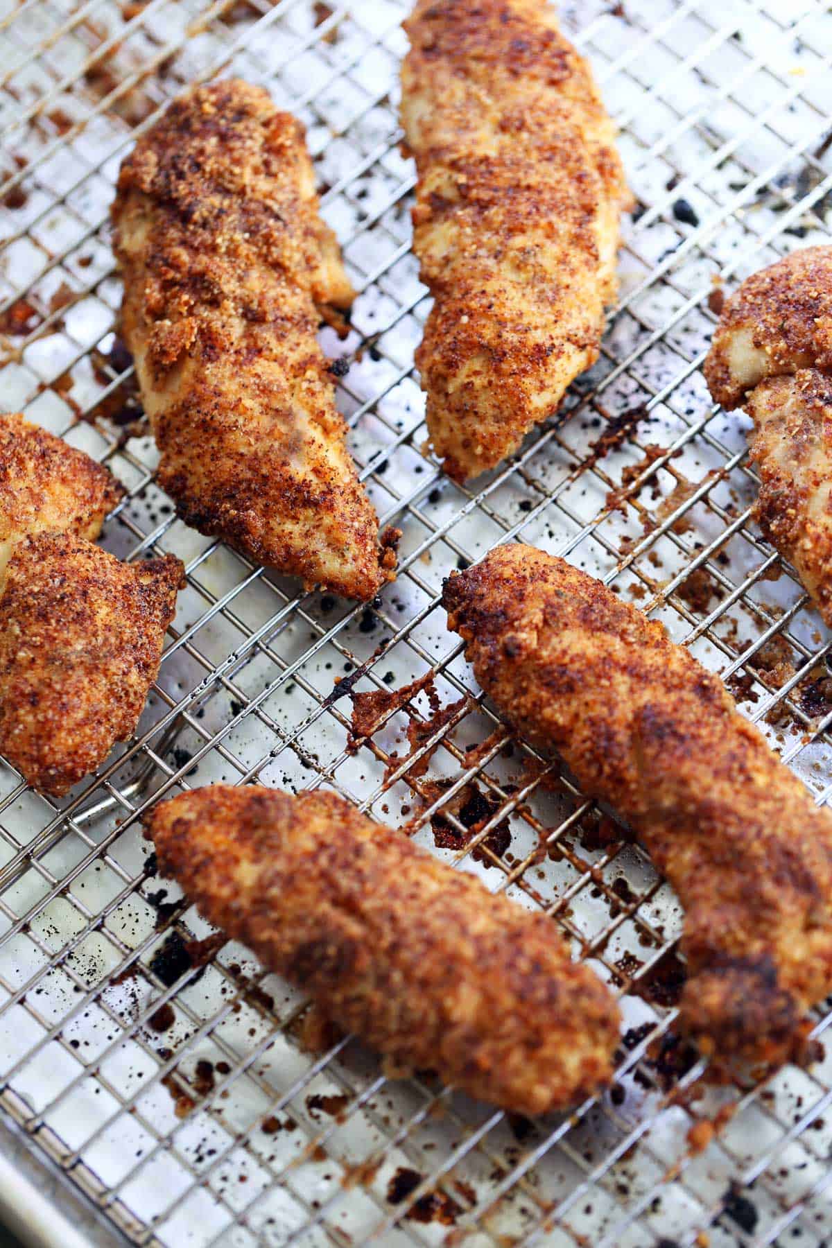 Almond flour chicken tenders are served on a baking sheet fitted with a rack.