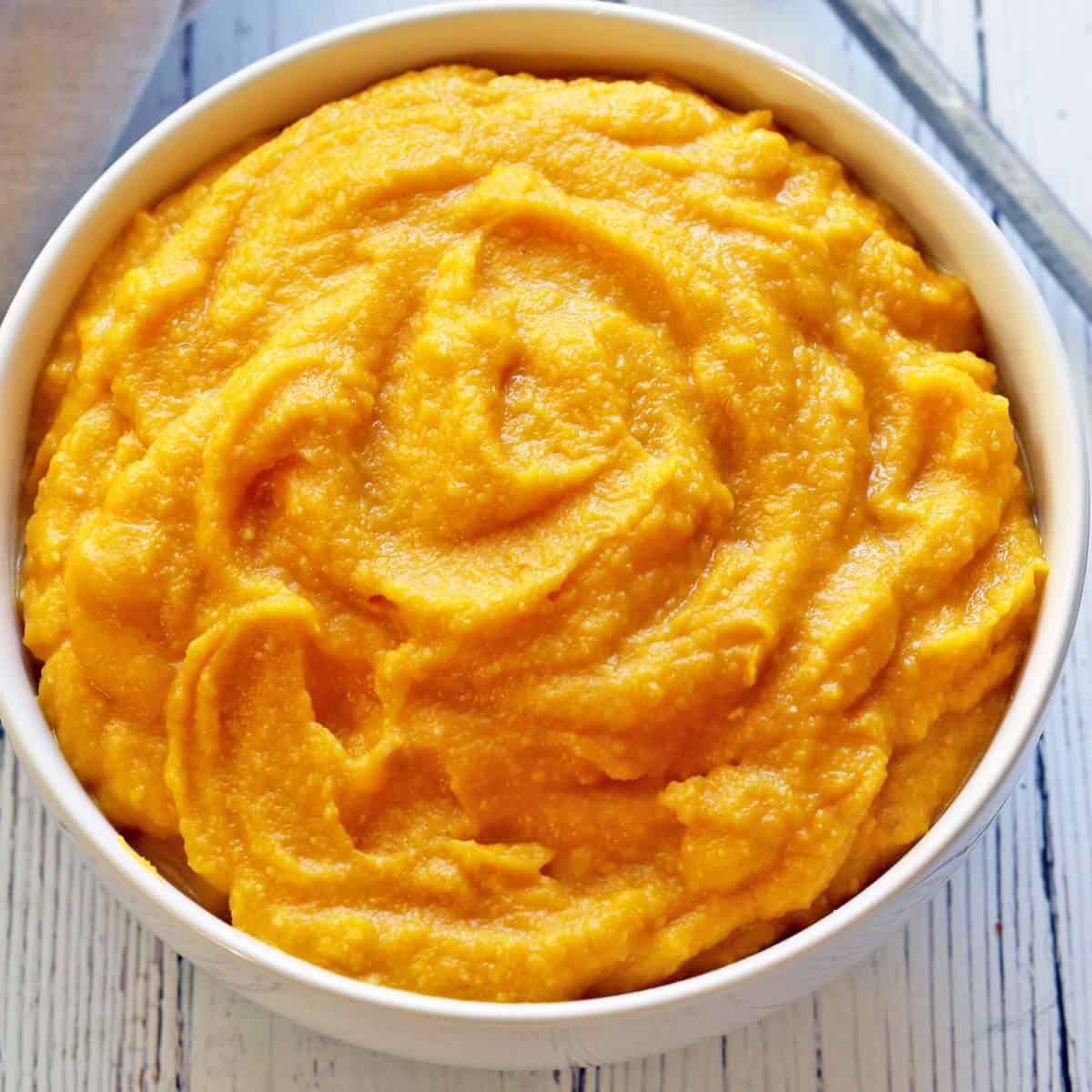 Mashed pumpkin is served in a white bowl.
