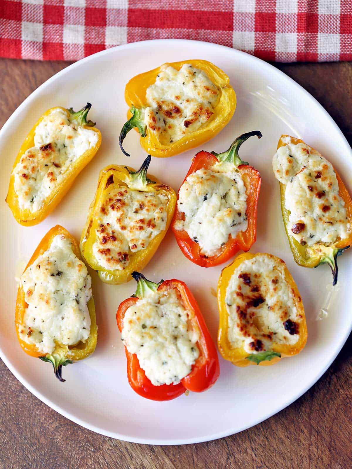 Stuffed mini peppers are served on a white plate. 