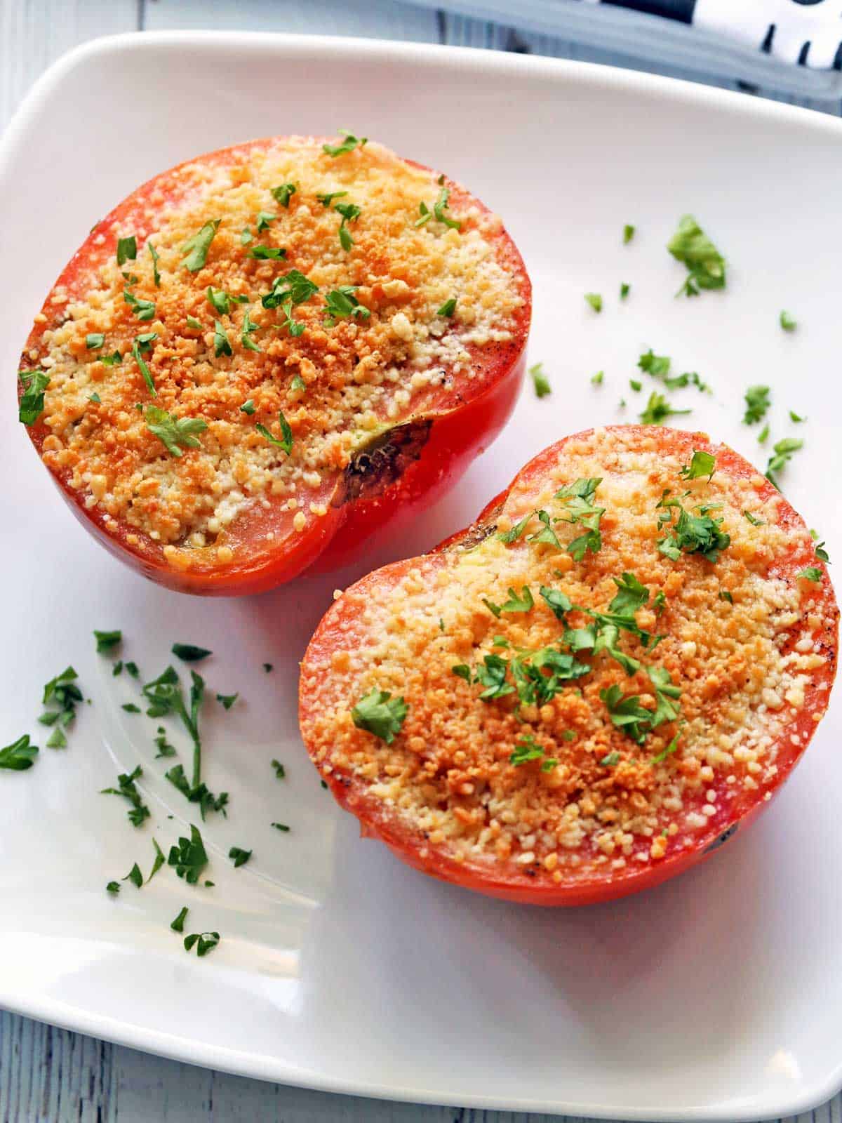 Broiled tomatoes are served in a white ceramic baking dish. 