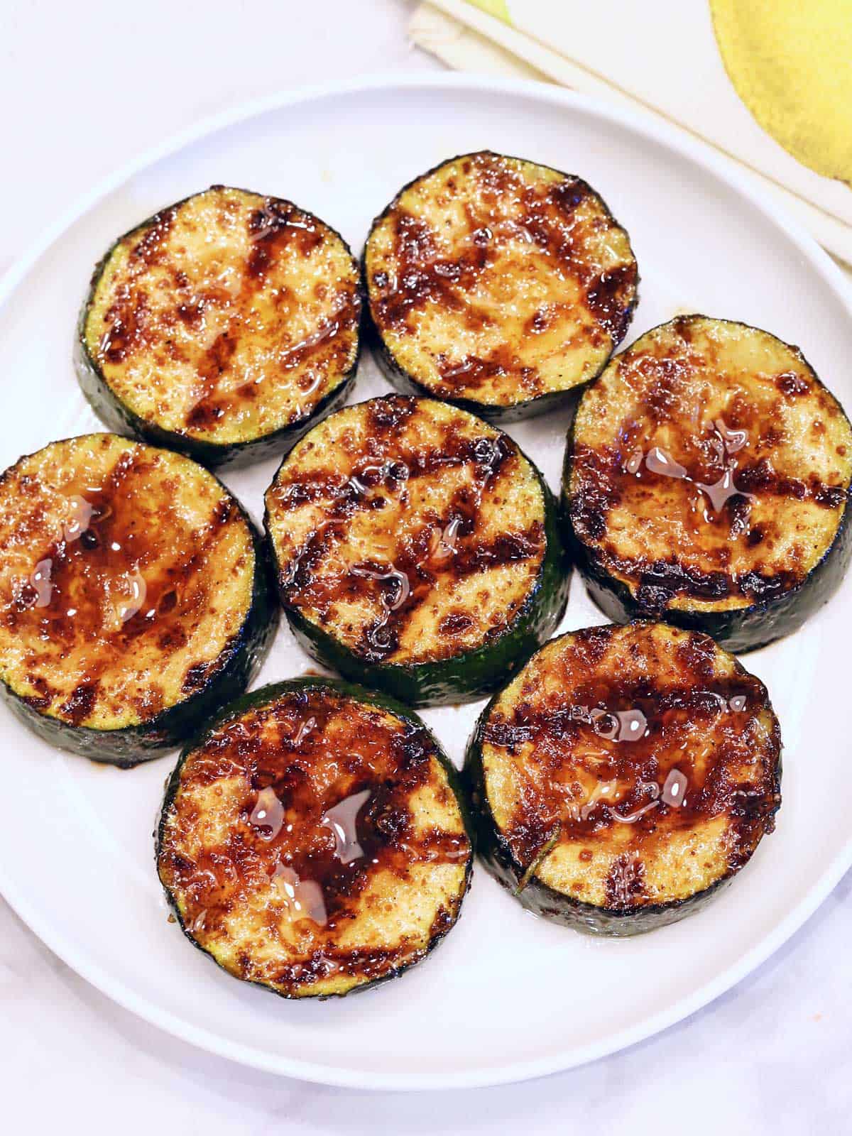 Grilled zucchini slices are served on a white plate. 