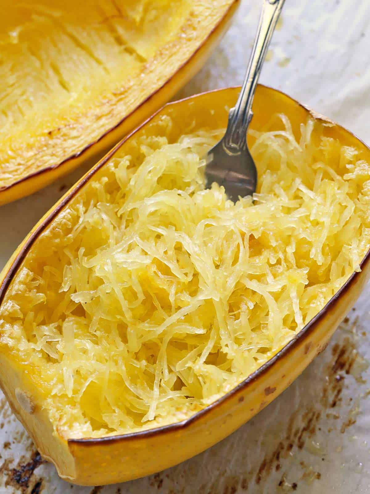 Baked spaghetti squash is served on a baking sheet with a fork.  