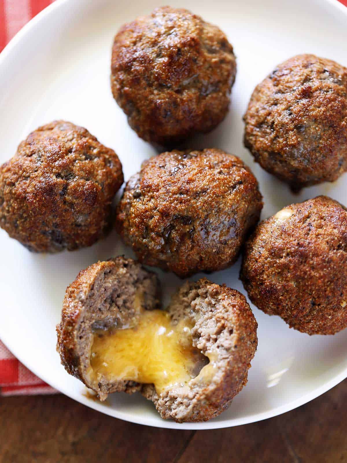 Cheese stuffed meatballs are served on a white plate. 
