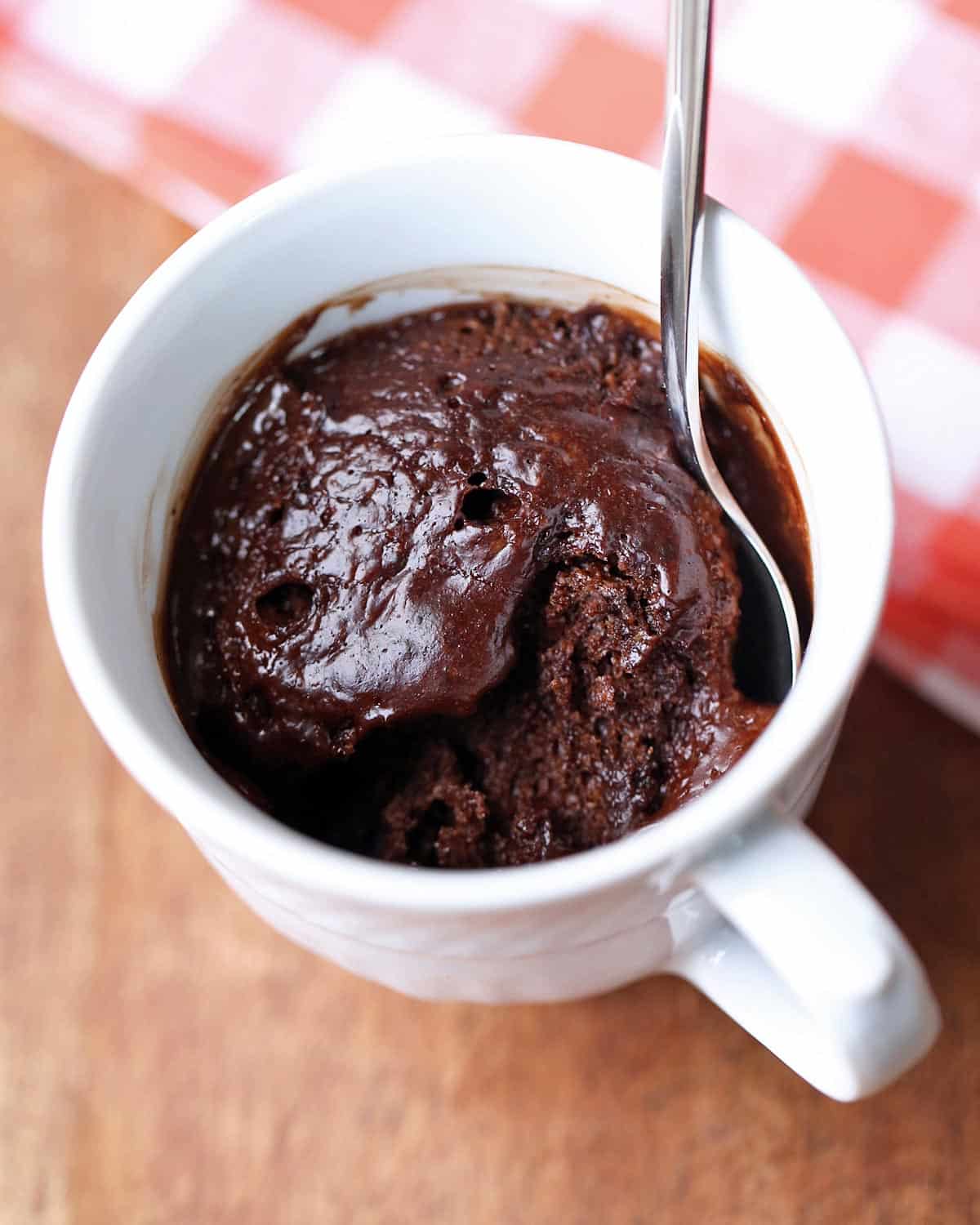 Keto chocolate mug cake is served in a white mug with a spoon.