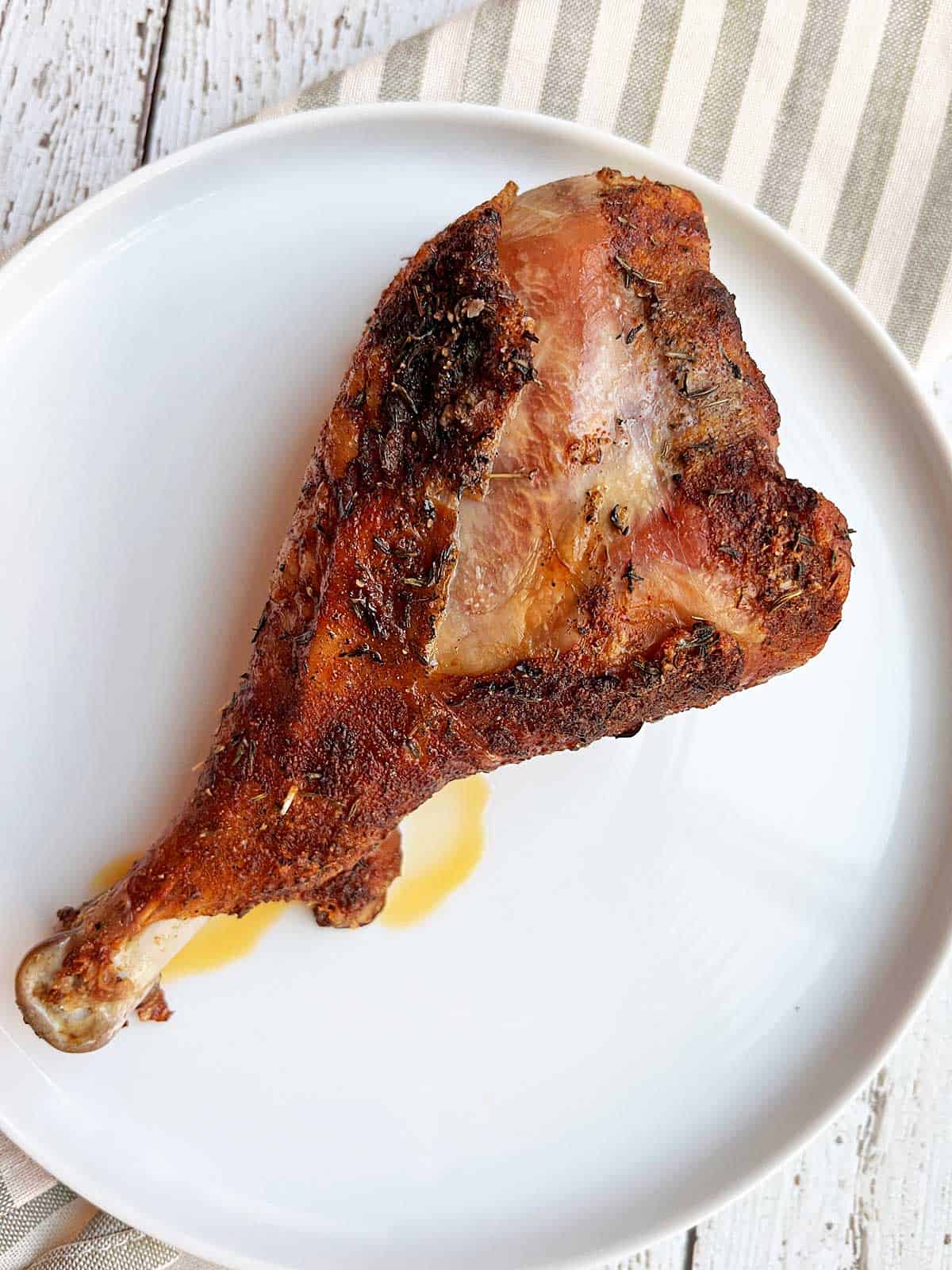 A large turkey leg is served on a white plate. 