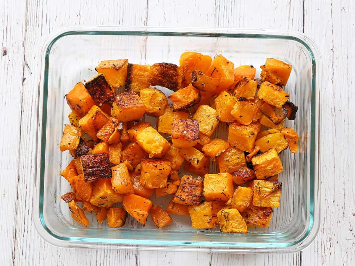 Roasted butternut squash leftovers are stored in a glass food storage container.