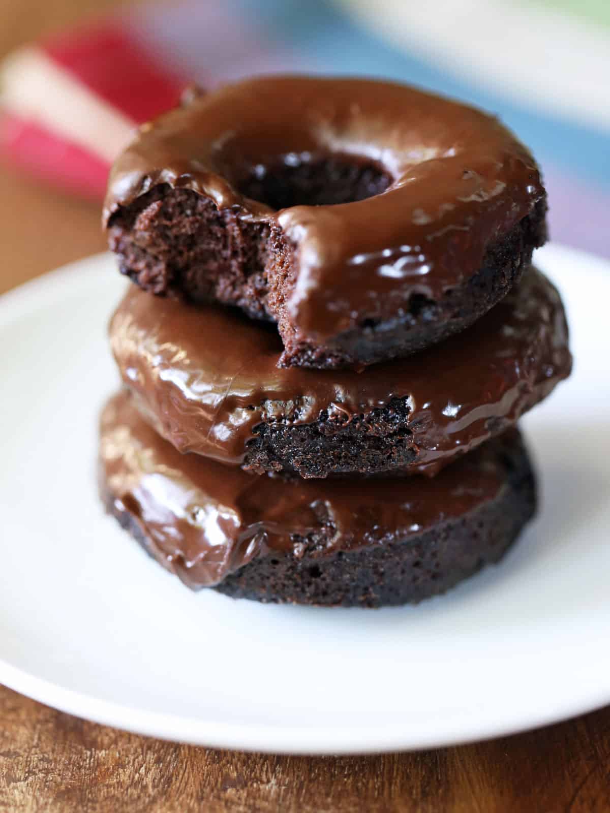 Three keto donuts are stacked on a white plate.