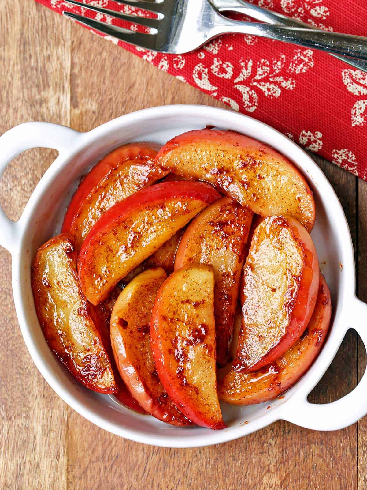 Baked apple slices are served in a white bowl. 