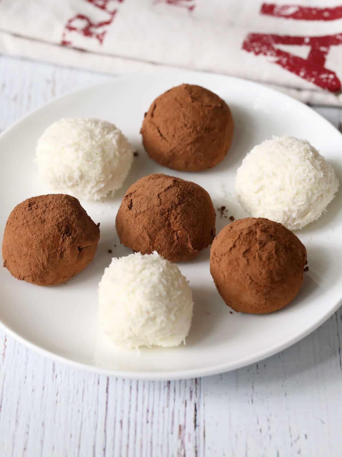 Keto cheesecake bites are coated with cocoa powder and shredded coconut.