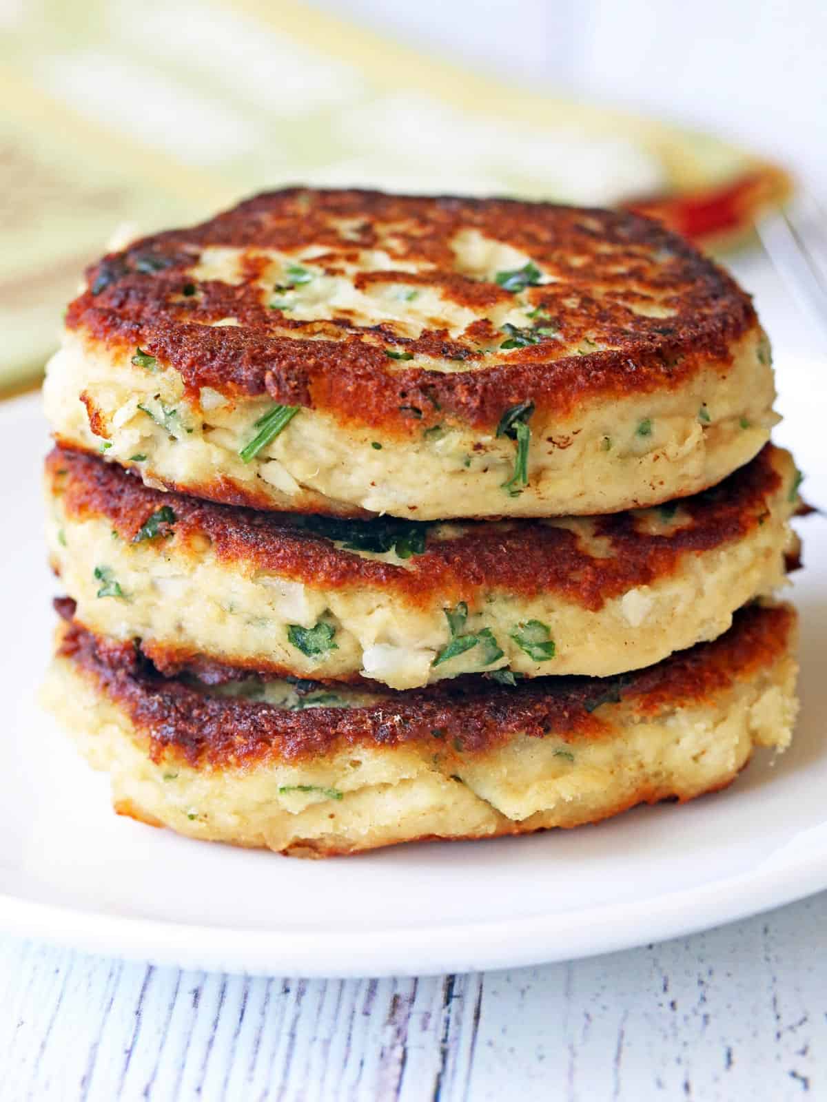 Three turkey patties are stacked on a white plate.