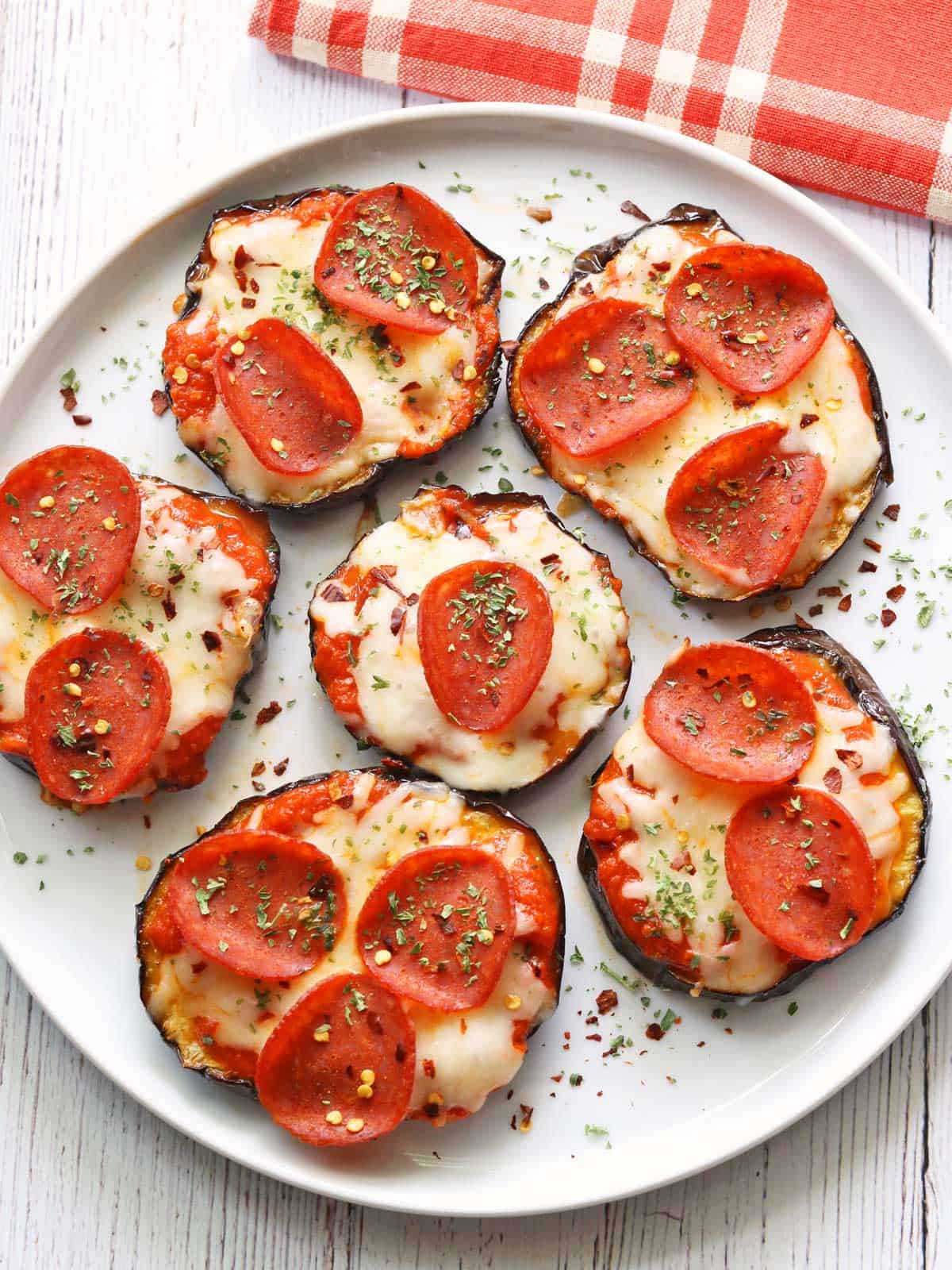 Eggplant pizza rounds are served on a white plate. 
