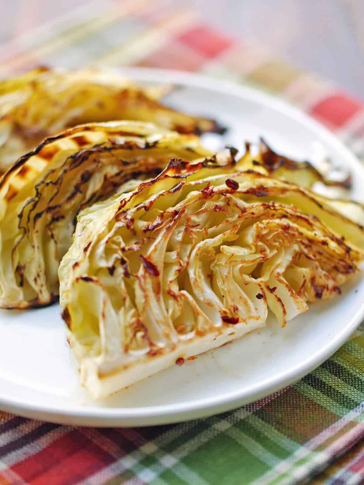 Roasted cabbage is served on a white plate.
