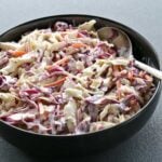 Homemade coleslaw is served in a black bowl.