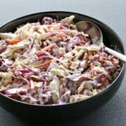 Homemade coleslaw is served in a black bowl.