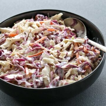Homemade coleslaw is served in a black bowl.
