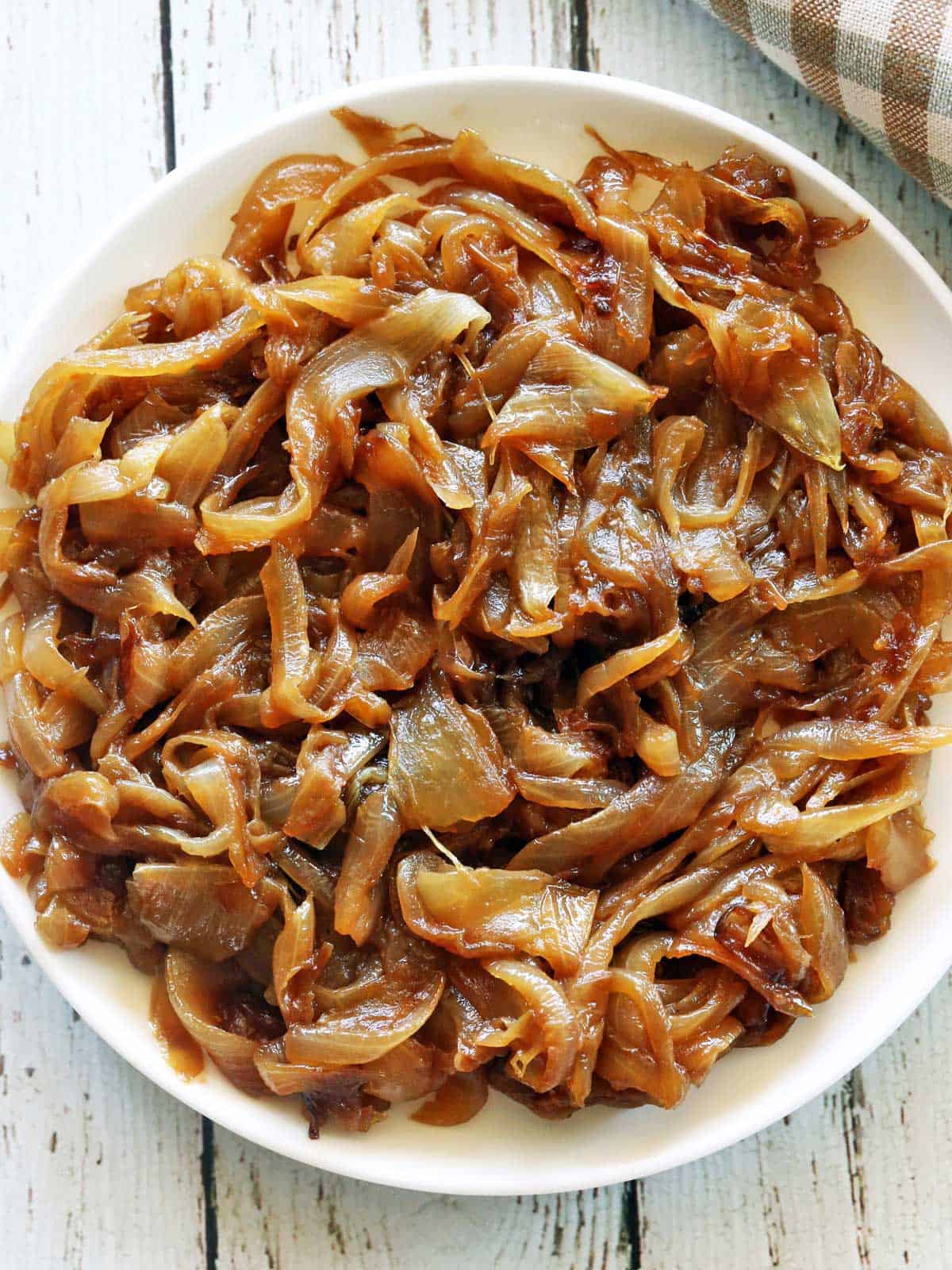 Caramelized onions are served on a white plate with a napkin.