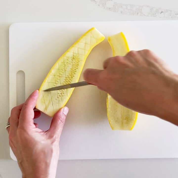 Scoring the flesh of yellow squash.