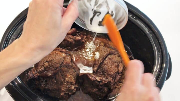 Adding a cornstarch slurry to the slow cooker.