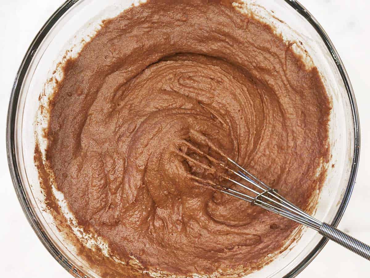 Adding almond flour and cocoa powder to the batter of a keto chocolate cake.