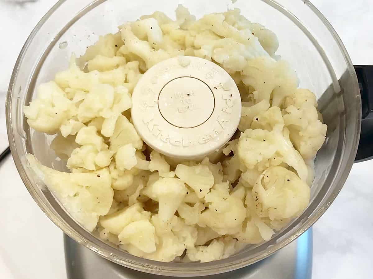 Adding the cauliflower to the food processor's bowl.