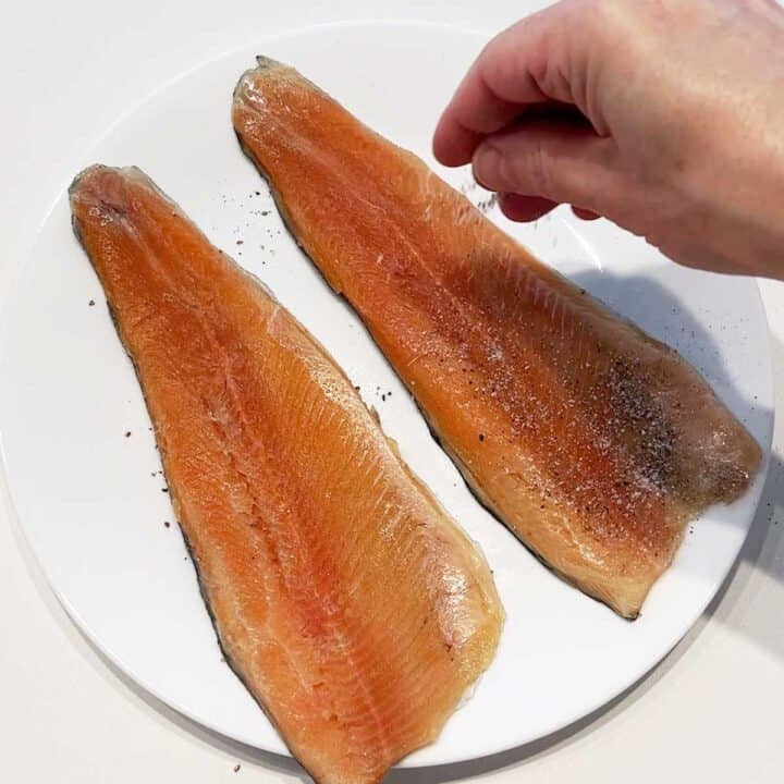 Seasoning rainbow trout fillets.