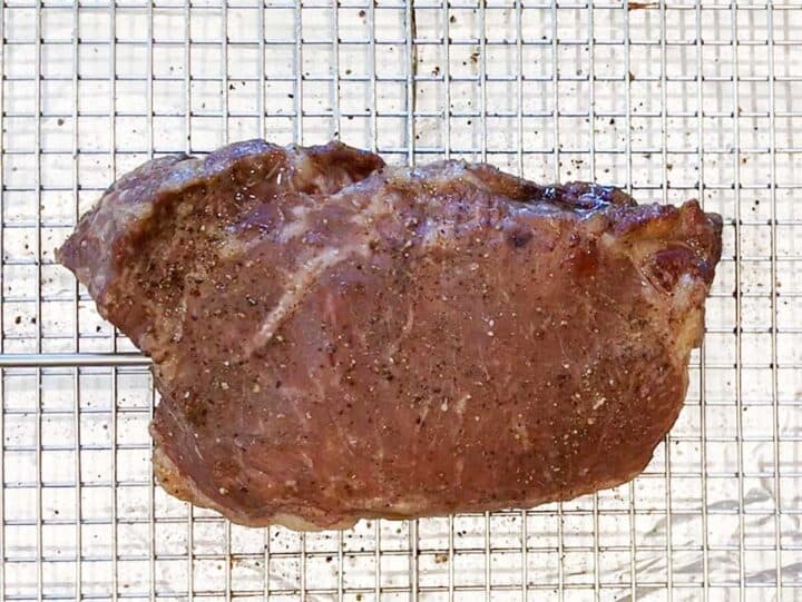 The steak in the pan after baking in the oven and before searing.