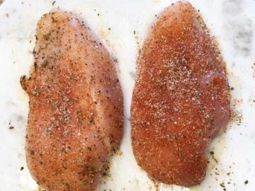 Seasoning the chicken breasts.