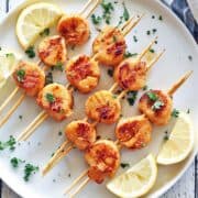Grilled scallops are served with lemon slices.